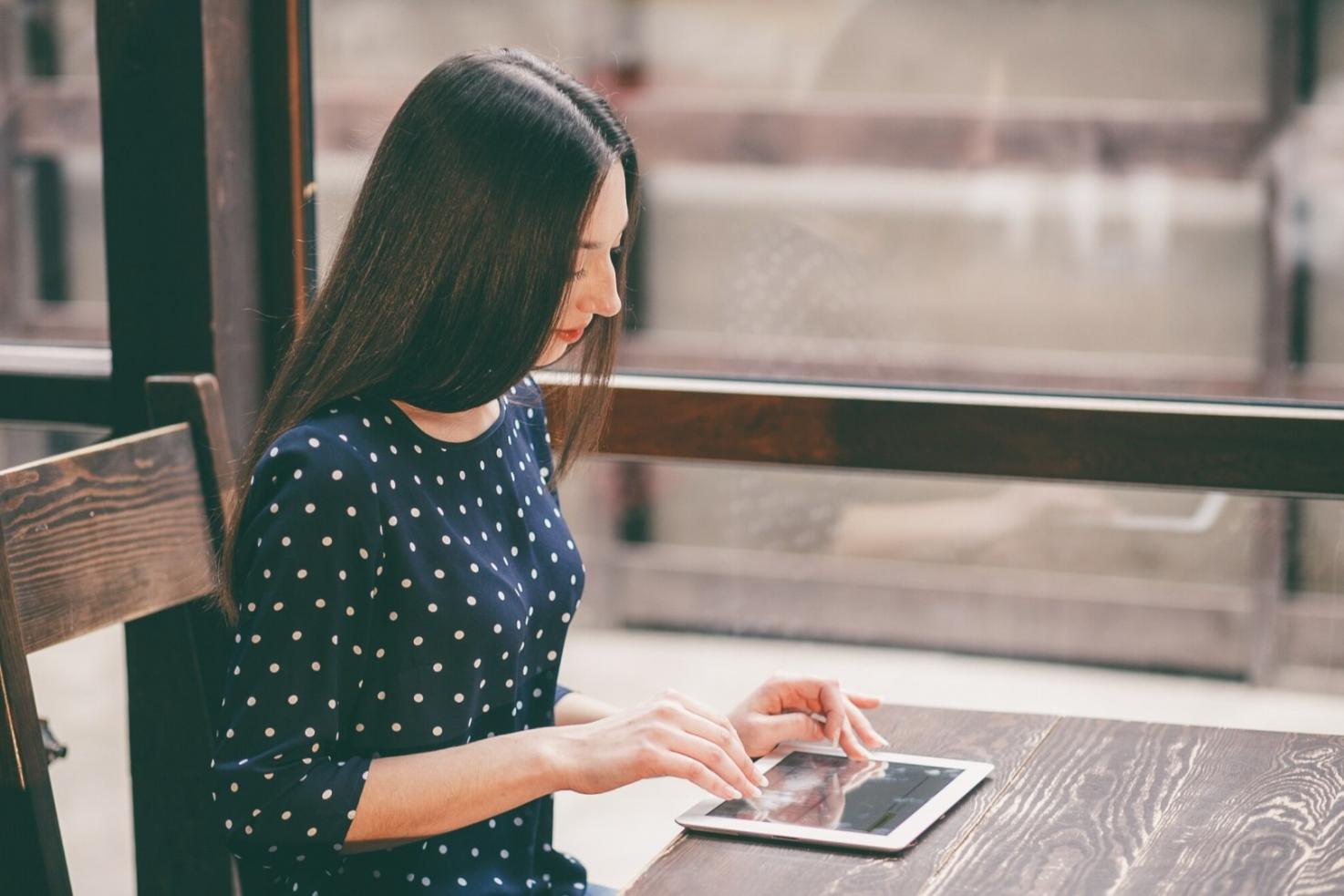 Person working on laptop with financial documents spread on desk, showing flexible learning environment